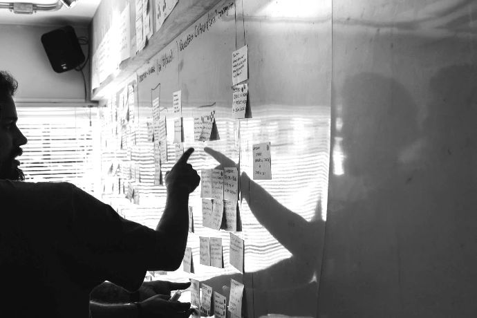 person pointing white paper on wall